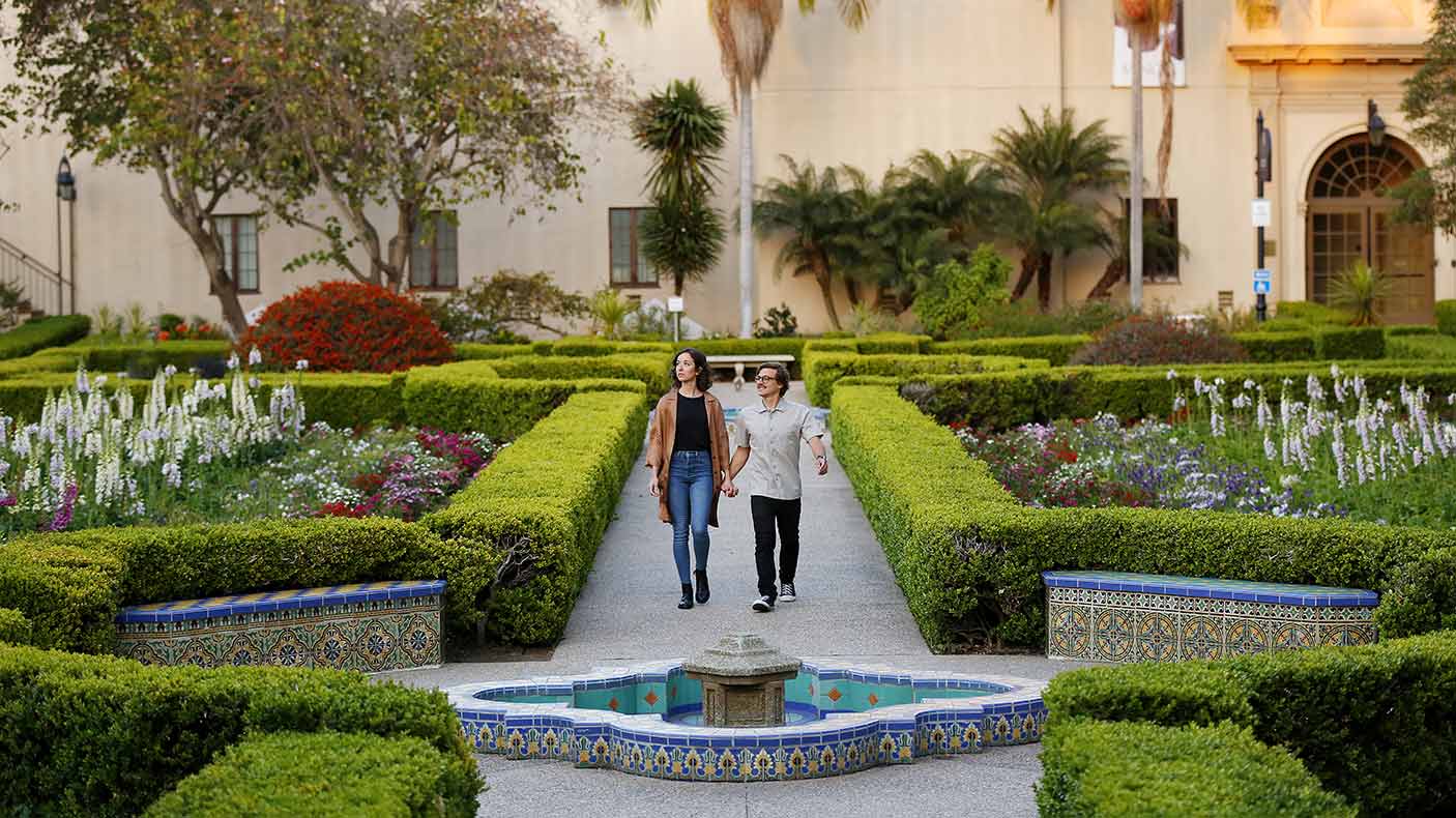 A couple walks through a garden at Balboa Park